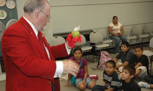 A club member performs a trick for a group of children